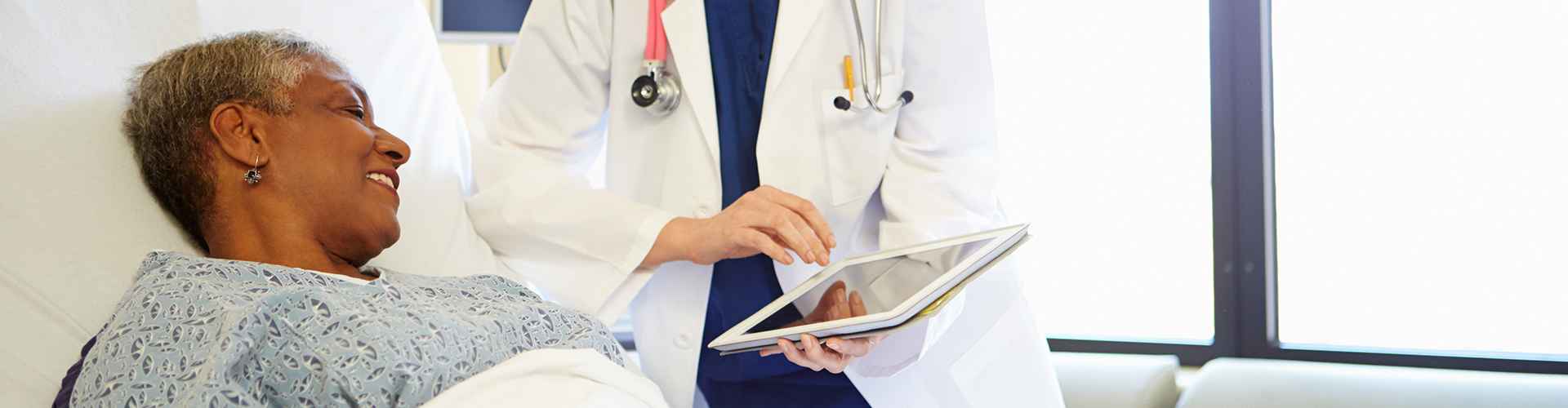 Doctor showing tablet to a patient in a hospital bed