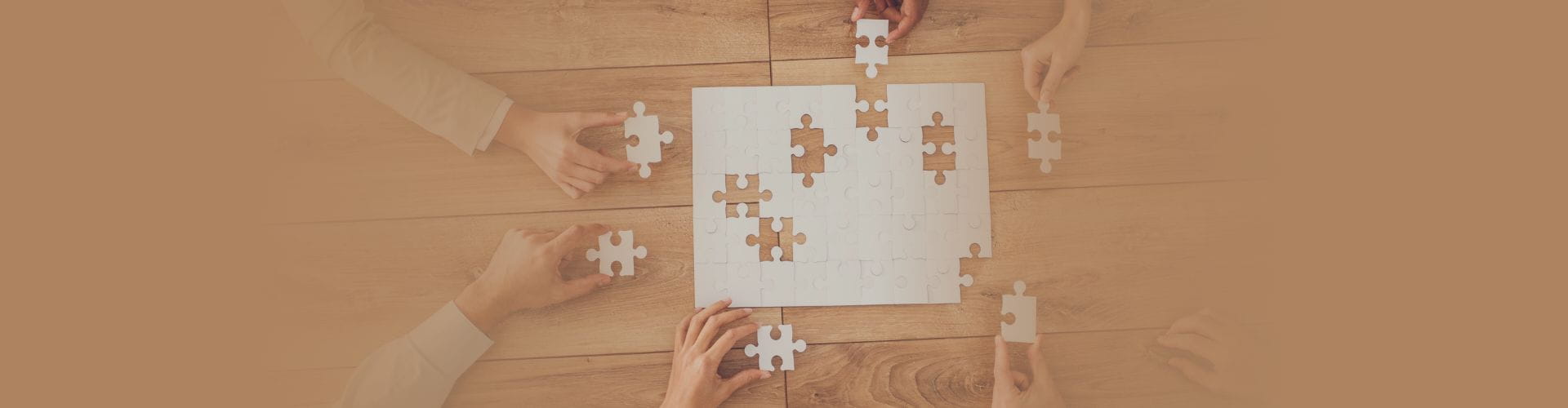 close up of 6 hands working on puzzle